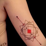 Фото тату: абстрактный геометрический рисунок на руке, состоящий из красных и коричневых линий, образующих ромбовидную структуру с красным квадратом в центре.