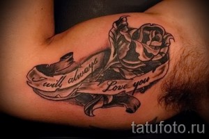 Фото тату: Реалистичная татуировка розы с лентой, на которой написана фраза 'I will always Love you', выполненная в черно-серых тонах на руке.