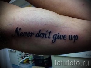 Фото тату: Простая татуировка надписи 'Never don't give up', выполненная черным цветом на предплечье, мотивирующая и вдохновляющая.