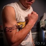 Фото тату: логотип Супермена на предплечье. Черно-серый рисунок, четкие линии, символ силы и героизма, тату на руке.