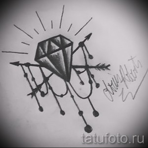 Черно-белое фото татуировки с изображением бриллианта, окруженного летящими стрелами. Эскиз выполнен в графическом стиле с четкими линиями.