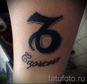 Фото простой татуировки знака зодиака Козерог с надписью 'Capricorn' на ноге. Минималистичный дизайн в черном цвете.