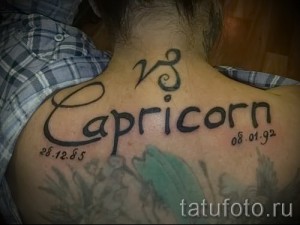 Фото тату Козерог на спине: надпись 'Capricorn' с датами рождения '28.12.85' и '08.01.92', выполненная черным контуром.