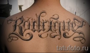 Фото тату надписи на спине: имя 'Rodriguez' выполнено в сложном готическом стиле с декоративными элементами.