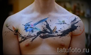 Фото тату: акварельная татуировка на груди, изображающая птиц на ветке дерева, выполненная в мягких акварельных тонах с добавлением черных элементов.