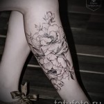 Фото татуировки с изображением пышных пионов на икре. Выполнена в технике blackwork, с акцентом на детализацию и тени.