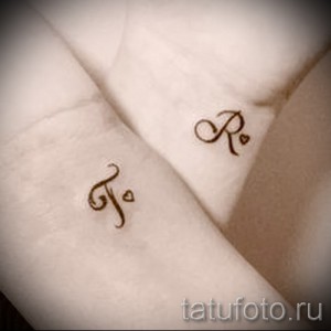 Фото тату: Парные татуировки с буквами 'F' и 'R', украшенными маленькими сердечками, на запястьях. Нежные и романтичные татуировки.