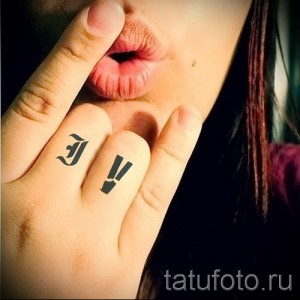 Фото тату букв "J" и "V" на пальцах девушки. Черные чернила, минималистичный стиль. Идеи для тату на пальцах.