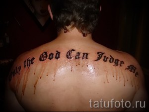 Фото тату с готической надписью "Only God Can Judge Me" на спине. Черные буквы с эффектом капающей крови. Смелый и провокационный рисунок татуировки.