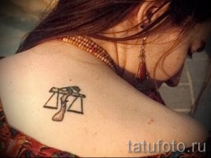 Фото тату: небольшая татуировка знака зодиака Весы на плече. Изящный и женственный дизайн.
