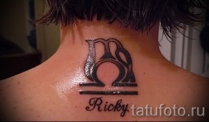 Фото тату: черный рисунок знака зодиака Весы на задней части шеи с надписью 'Ricky'. Стильная и персонализированная татуировка.