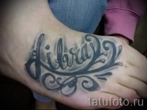 Фото тату надписи 'Libra' на стопе, выполненной в черных тонах с декоративными завитушками. Изящный рисунок татуировки для поклонников знака зодиака.