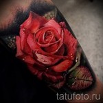 Фото тату реалистичной красной розы с каплями росы на лепестках. Детализированный рисунок татуировки на руке.