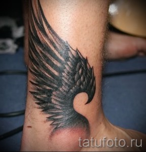 Фото тату: крупная татуировка крыла, выполненная в технике blackwork на лодыжке. Строгий и эффектный дизайн для мужчин и женщин.