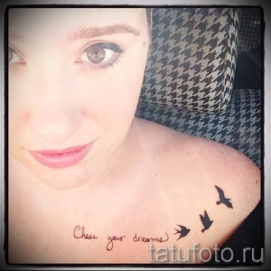 Фото татуировок трех ласточек и надписи "Chase your dreams" на женском плече. Черно-белый рисунок, выполненный в минималистичном стиле.