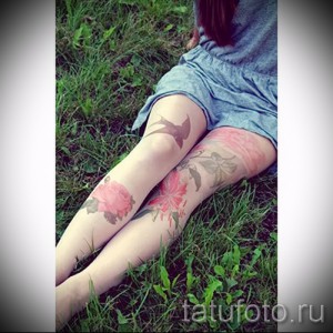 Фото тату: две татуировки ласточек, летящих среди роз, расположены на бедрах. Нежные цвета и романтичный стиль.