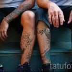 Фото тату на голенях двух людей, с изображением черепов, цветов и дракона в традиционном стиле. Яркие цвета и детализированная проработка.