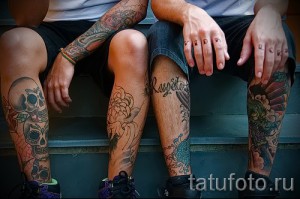 Фото тату на голенях двух людей, с изображением черепов, цветов и дракона в традиционном стиле. Яркие цвета и детализированная проработка.