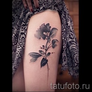 Фото тату в стиле акварель с изображением цветка на бедре. Мягкие переходы цветов и нежные оттенки.