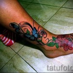 Фото тату: красочная татуировка с изображением бабочки и цветущих веток, обвивающих лодыжку. Идеальный эскиз для девушек, любящих природу.