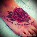 Фото татуировки на стопе: красная роза с надписью "The Worst Things Beautiful". Символизм красоты в страданиях.