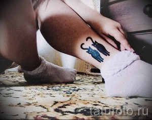 Фото тату двух силуэтов кошек на лодыжке. Черный рисунок татуировки выполнен в минималистичном стиле, идеально подходит для любителей кошек.