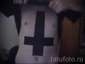 Фото тату: крупный черный перевернутый крест на груди мужчины, вид спереди.