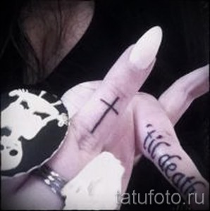 Фото тату маленького креста на пальце руки и надписи 'til death' на другой руке. Символизирует верность и преданность.