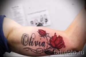 Фото татуировки: надпись "Olivia" с изображением красной и бутона розы на руке, выполненная в акварельном стиле.