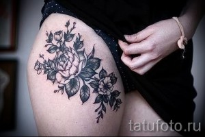 Фото тату: реалистичный букет роз и листьев в технике blackwork на женском бедре. Детализированный рисунок татуировки с плавными линиями и тенями.