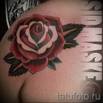 Фото татуировки с красной розой на плече. Реалистичный рисунок с детально проработанными лепестками и листьями. Идеально для любителей цветочных мотивов.