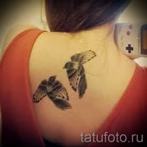 Фото татуировки с изображением двух летящих синиц, выполненной в черно-белой гамме, с акцентом на детализацию крыльев.
