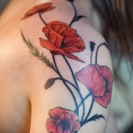 Фото тату маков на плече. Рисунок выполнен в ярких красных и зеленых тонах, с акцентом на детализацию лепестков и стеблей. Идеально для любителей цветочных мотивов.