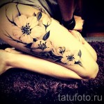 Фото тату цветущей сакуры на бедре. Рисунок выполнен в мягких розовых и черных тонах, с акцентом на детализацию лепестков и ветвей. Идеально для женственного образа.