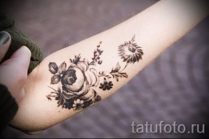 Фото тату нежных цветов и листьев на запястье. Черно-белый рисунок татуировки с тонкой проработкой деталей.