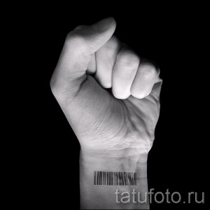 Фото тату штрих-кода на запястье. Черно-белый рисунок татуировки, выполненный в минималистичном стиле. Рука в кулаке.