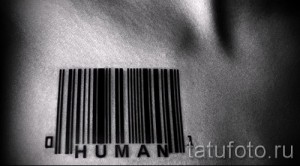Фото тату штрихкода с надписью 'HUMAN' на груди. Черно-белый минималистичный рисунок татуировки, подчеркивающий ценность человеческой жизни.