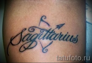 Фото тату: надпись "Sagittarius" (Стрелец) с изображением стрелы, выполненная черными линиями на руке. Символ зодиака и стремления к цели.