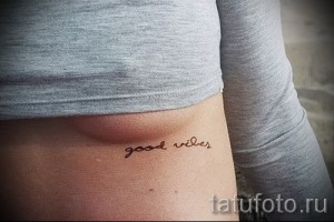 Фото минималистичной тату надписи 'good vibes' коричневым цветом, расположенной на боку.