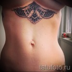 Фото тату: геометрическая мандала, расположенная на животе. Черно-серый рисунок татуировки с тонкими линиями и сложным узором. Идеально для тех, кто ценит гармонию.