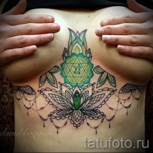 Фото тату: изображение чакры Аджня (третий глаз) с лотосом и декоративными элементами на груди. Яркие цвета, восточный стиль.