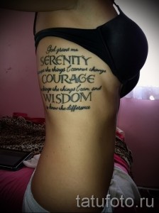 Фото татуировки с цитатой "God grant me Serenity, Courage, Wisdom" на боку, выполненной черным цветом. Длинная надпись, расположенная вертикально.
