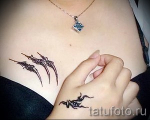 Фото тату: стильный трайбл рисунок, расположенный на животе и руке. Черные узоры создают эффектный и загадочный образ.