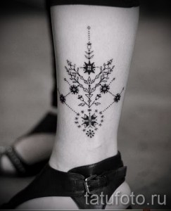 Фото тату на лодыжке: сложный узор, выполненный в технике dotwork. Детализированный рисунок татуировки в черном цвете с небольшими акцентами.