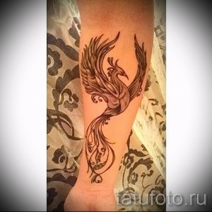 Фото татуировки феникса на предплечье, выполненной в стиле графика. Четкие линии и детализированное изображение.