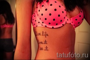 Фото тату надписи "live life. love it. do it." на женском боку. Черно-белый рисунок татуировки, выполненный в каллиграфическом стиле.
