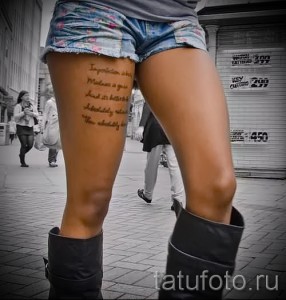 Фото тату: длинная надпись на внутренней стороне бедра девушки, выполненная коричневыми чернилами. Текст расположен вертикально, вдоль линии бедра.