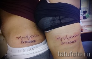 Фото парных татуировок на боку, изображающих кардиограмму с сердечком и римскими цифрами, обозначающими дату.