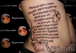 Фото тату: татуировка с надписью на иностранном языке и изображением цветка на боку, выполненная в коричневых и розовых тонах.