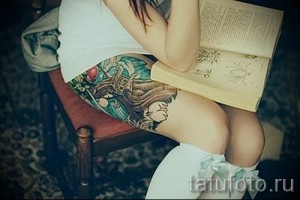 Фото тату: красочная татуировка дракона на женском бедре. Детализированный рисунок с использованием ярких цветов и плавных линий.
